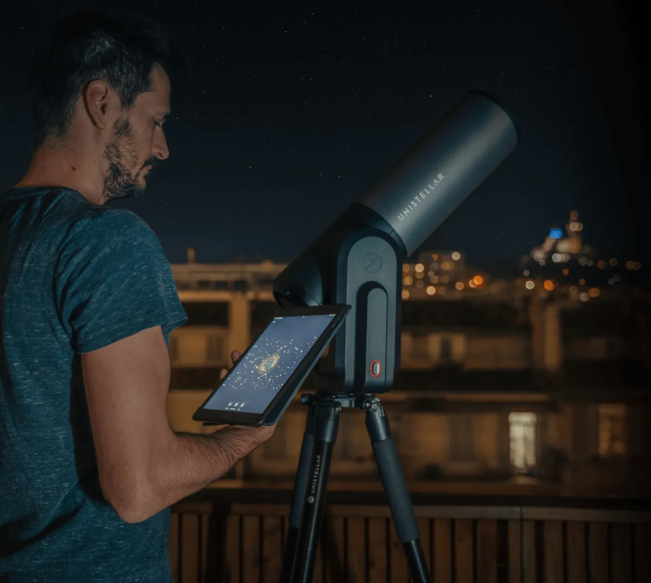 Un homme pilote l'eQuinox 2 depuis sa tablette, sur un balcon la nuit. Les lumières de la ville éclairent l'arrière-plan.